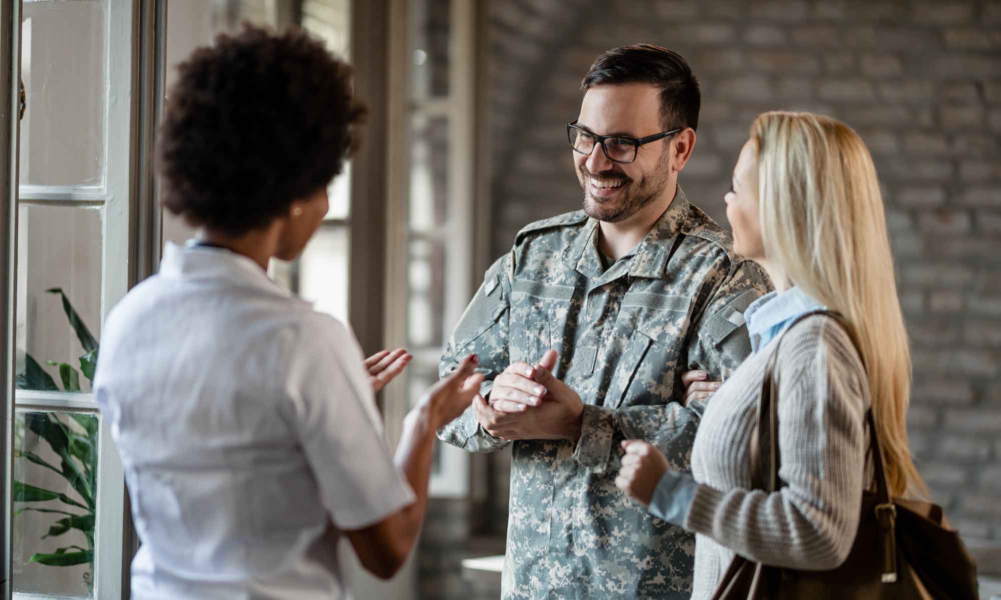 Military man conversing with two other people