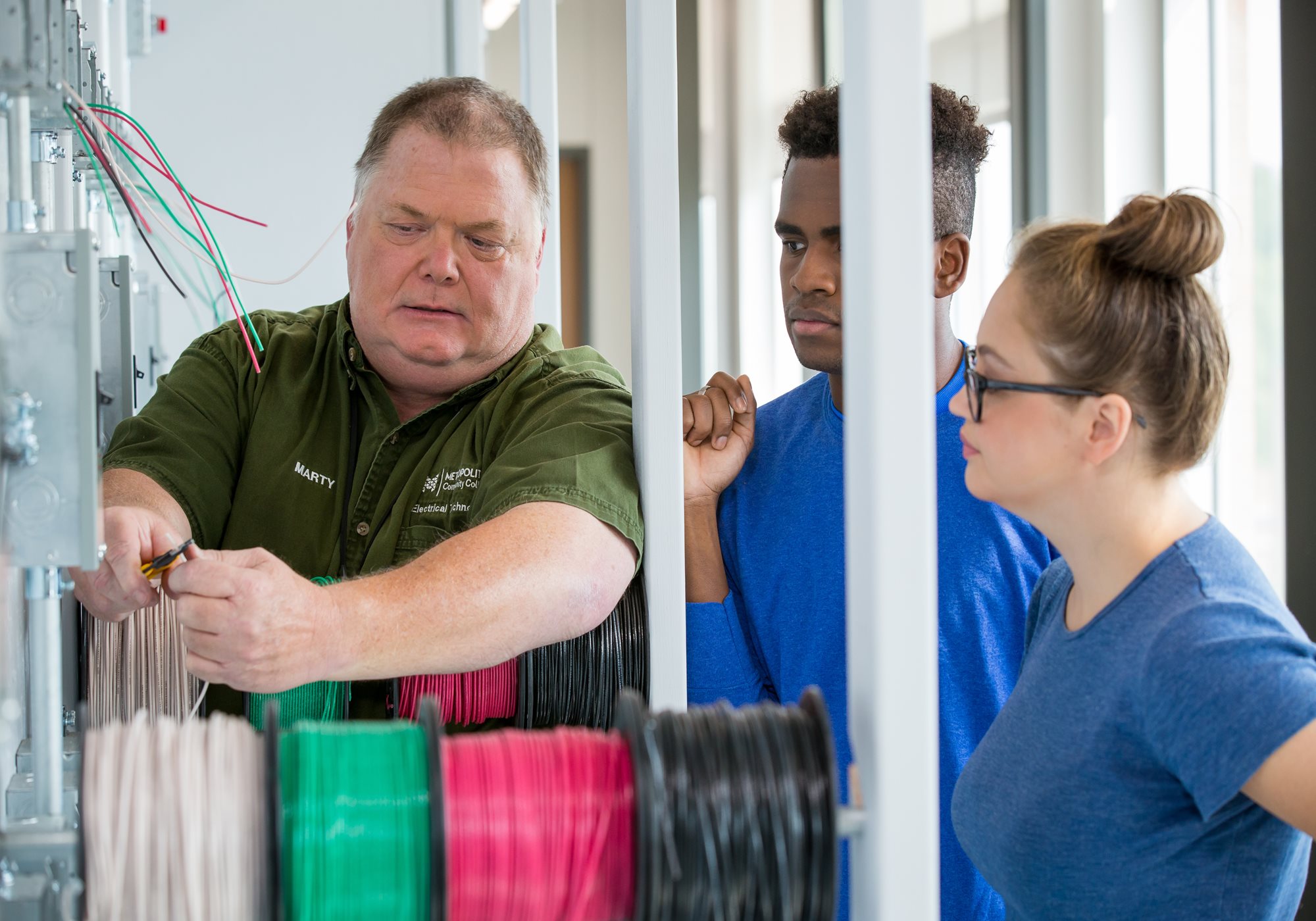 Instructor instructing two students on electrical wiring