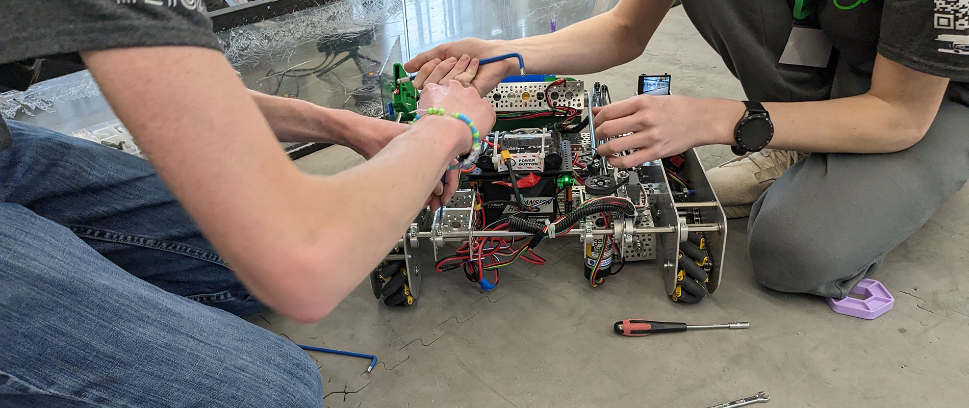 Two young students working on a robot used in a competition