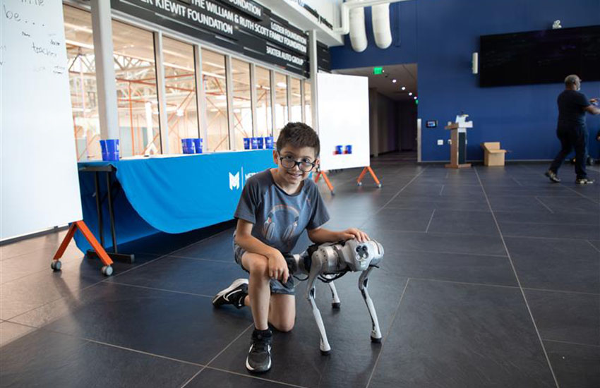 A child poses with Gizmo, a robotic dog