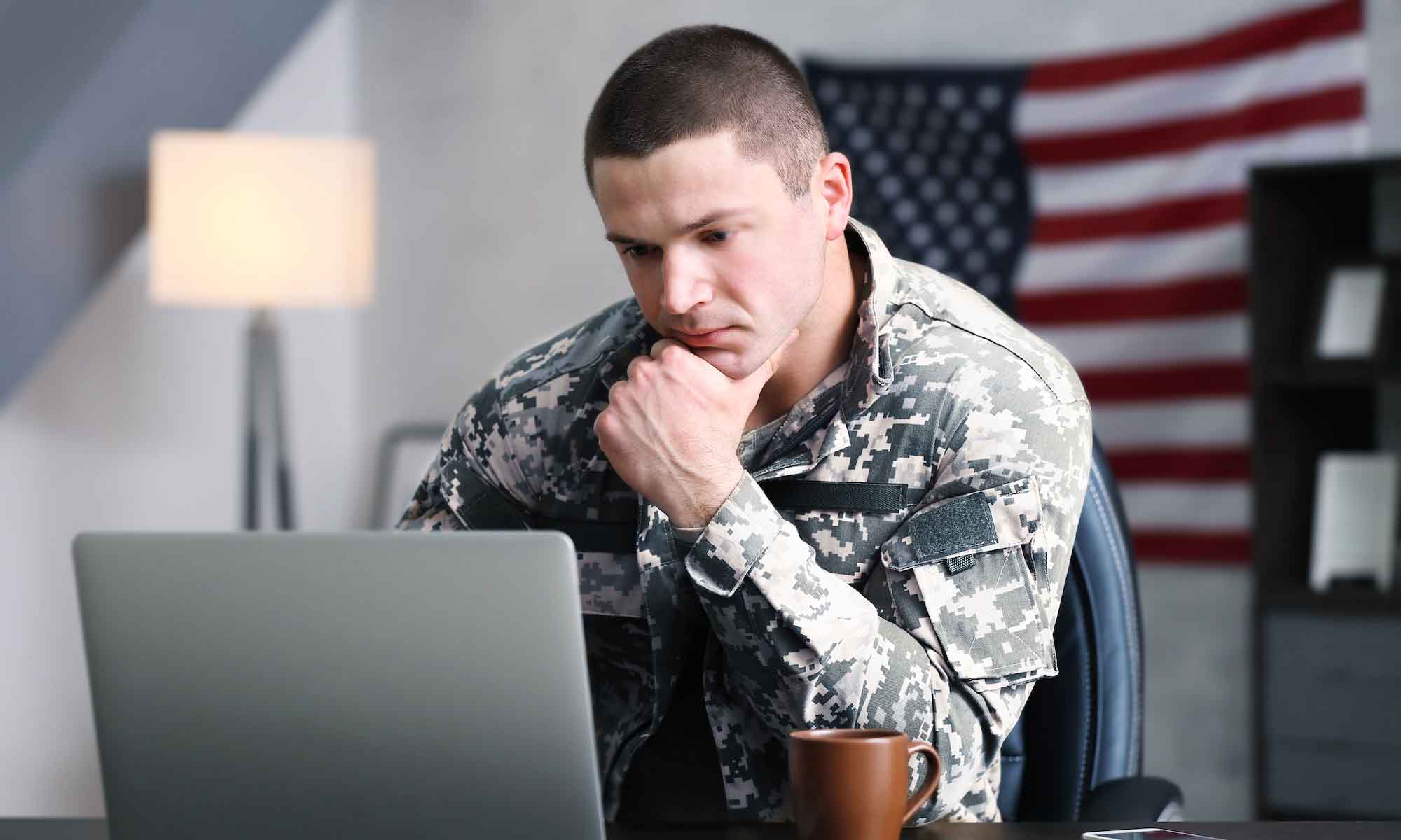 Military person sitting at desk working on laptop
