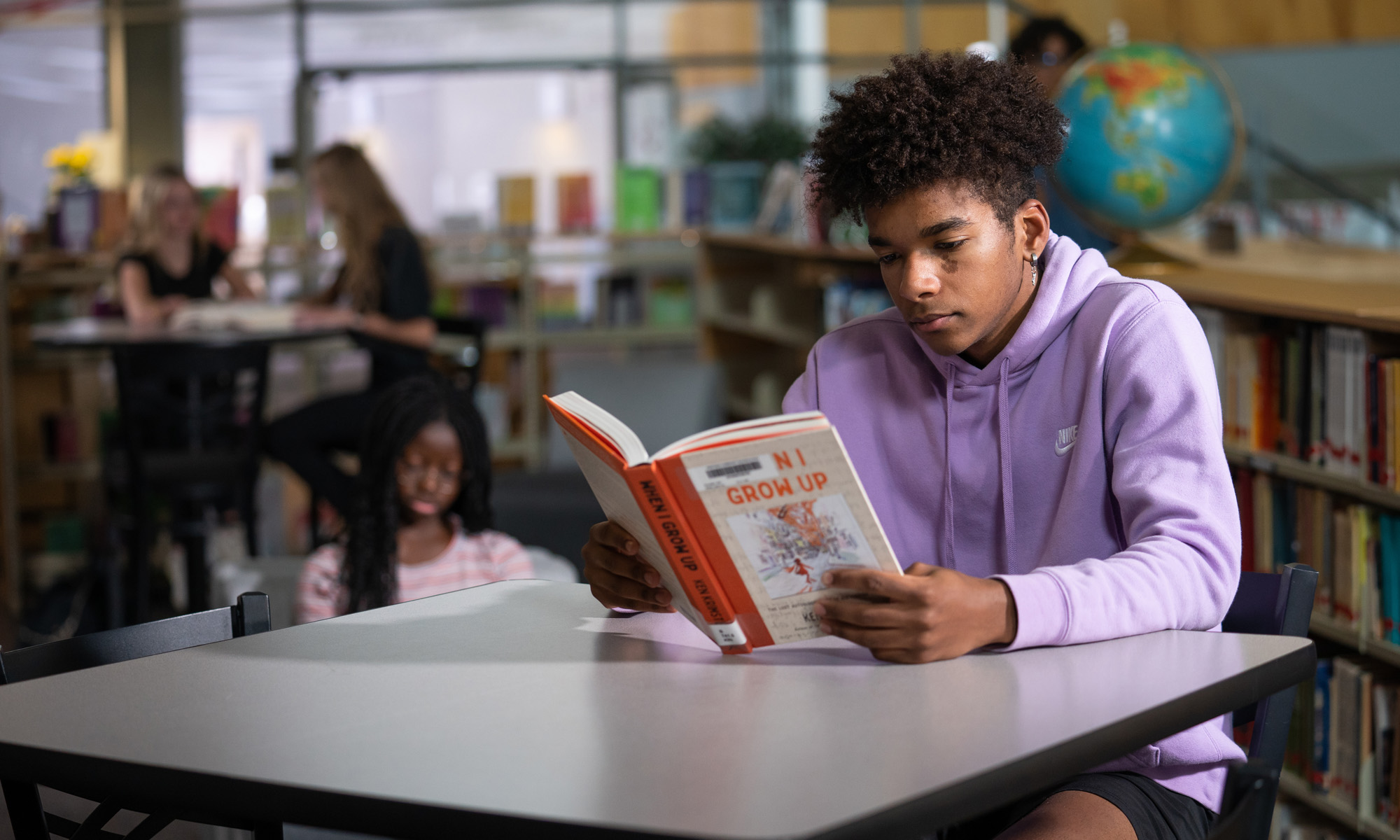 Male student reading a booking in the library