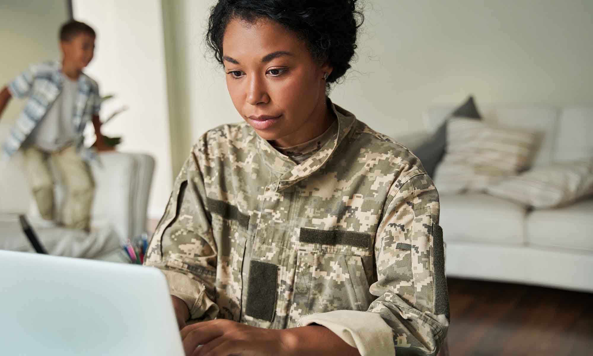Military person working on laptop in livingroom