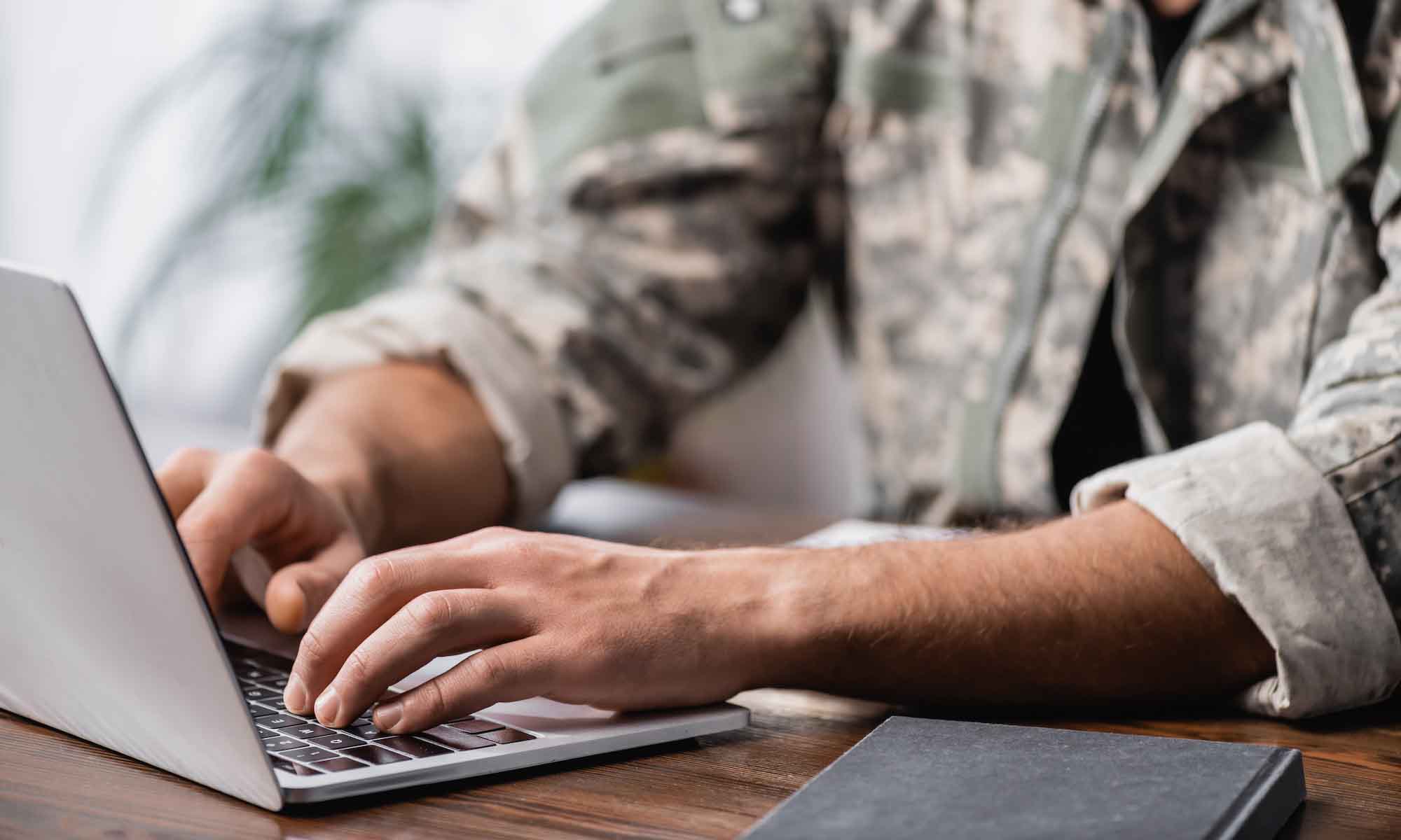 Person in military gear working on laptop
